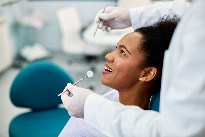 lady sitting in dental chair smiling while dentist holds tools above
